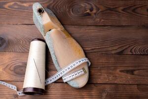 Leather samples for shoes and wooden shoe last on dark wooden table. photo