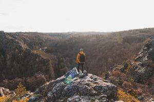 viajero en un amarillo chaqueta en pie en el borde de un rock disfrutando un momento de relajación y un ver de el divorciar sarcasmo valle, praga, checo república. lograr éxito foto