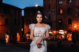 un novia en un blanco vestir en el antiguo pueblo de san gimignano.a niña camina alrededor el ciudad en italia.toscana. foto