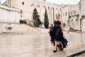 A stylish bride in a black wedding dress poses in the ancient French city of Avignon. Model in a beautiful black dress. Photo shoot in Provence.