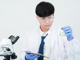 Portrait asian man student scientist doctor in shirt gown one person wokk job plant looking hand holding control microscope on white table see the results of scientific experiments inside laboratory photo