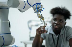 aprendiz robótica ingeniero aprendizaje con programación y manipulando robot mano, industrial robótica diseño, alto tecnología instalación, moderno máquina aprendiendo. masa producción automáticas. foto