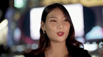 asiatico donna multi-razza Bellissima. attività commerciale donna utilizzando smartphone su un' città strada con neon bokeh luci splendente a notte. donna guardare a mobile Telefono a piedi nel strada con illuminazione su tabellone. video