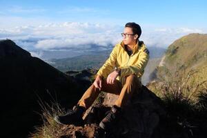 encima nube nueve, montar batur cima, asiático hombre excursionista debajo azur cielo y nube mar foto