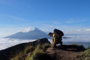 Above Cloud Nine, Mount Batur's Peak, Asian Man Trekker under Azure Sky and Cloud Sea photo