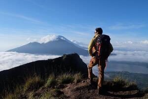 encima nube nueve, montar batur cima, asiático hombre excursionista debajo azur cielo y nube mar foto