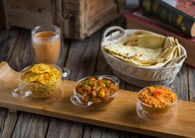 Assorted break fast set balalet or balaleet, aloo nakhi,aloo karahi, tomato egg with bread and coffee served in a dish isolated on cutting board side view of breakfast on wooden background photo