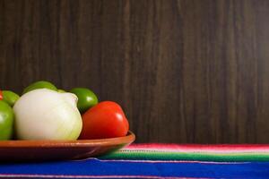 Fruits and vegetables in traditional Mexican clay pots on colorful serape. Cinco de Mayo celebration background. photo