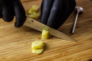 Person with black gloves Peeles and cuts ginger photo