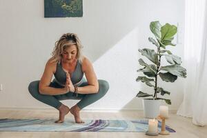 A 50-year-old woman doing online yoga at home photo