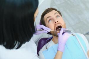 hombre teniendo un visitar a el del dentista. hermoso paciente sentado en silla a dentista oficina en dental clínica. foto