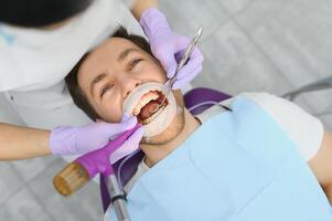 hombre teniendo un visitar a el del dentista. hermoso paciente sentado en silla a dentista oficina en dental clínica. foto