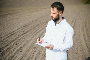 Agronomist studying samples of soil in field photo