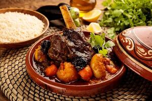 Moroccan lamb and Vegetables Tangine with bread served in a dish isolated on wooden background side view photo