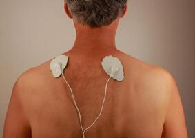 Man using an Electro Therapy Massager or Tens Unit on his back for pain relief of Muscles and Joint photo