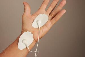 Man using an Electro Therapy Massager or Tens Unit on his hand for pain relief for Carpal Tunnel photo