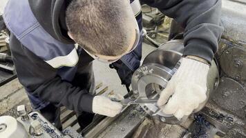 Close-up, top view, a young trainee worker measures a part with a caliper on a lathe and screwcutting machine video