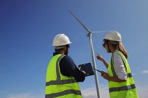 Wind turbine engineers working on the roof of car at a wind turbine field, checking and comparing the blueprint and condition of the Turbine's Electrical Power photo