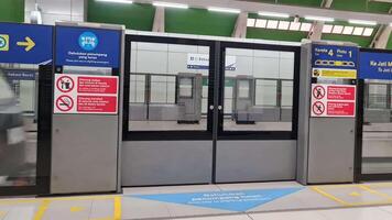 Bekasi, Indonesia on April 8, 2023. A closed passenger safety door at the Jabodebek LRT station. You can see an LRT train passing by, arriving at the station. video