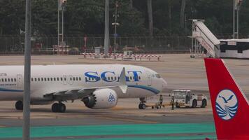 PHUKET, THAILAND FEBRUARY 26, 2023 Pushback tug with towbar attached with airplane SCAT. Ground support equipment in airport. Towbar attached to an aircraft video