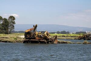 abandoned rusted bulldozer in Aveiro lagoon Ria de Aveiro located on the Atlantic coast of Portugal photo