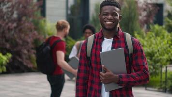 Happy smiling African American student teenager man guy male showing thumb up great cool reaction recommend good education studying enjoy like posing in city university talking multiracial students video