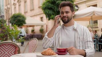 framgångsrik caucasian man talande mobil telefon smartphone ring upp stilig affärsman frukost kaffe croissant Kafé restaurang morgon- stad utanför finansiera kommunikation urban arbetsgivare arbetstagare chattar video