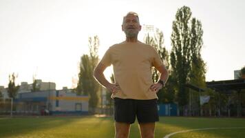 Old man warm-up pelvic muscles preparations before training athlete sportive lifestyle exercise sportsman wellbeing recreation health longevity stadium city outdoors pensioner physical activity cardio video