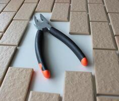 Rubberized Handles Of Pliers On Free Space On A Surface Covered With Brick Tiles. Home Repairing Square Stock Photo