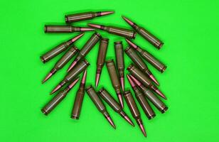 Unitary cartridges with copper bullets scattered on a green top view photo