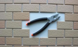 Opened jaws pliers on clean place of a missing tiles on a fully tiled surface photo