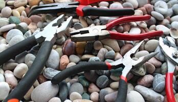 Different Pliers With Plastic Handles On A Round Sea Rocks Texture Background photo