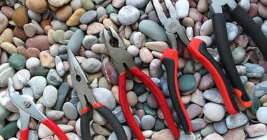 Stock Photo Of Slip Joint Pliers, Groove Pliers, Needle Nose Pliers And Linesman Pliers In Size Order On A Pebble Stones