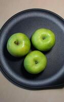 Three whole Granny Smith apples ready to be baked in a special pan photo