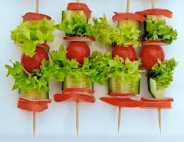 Top view of vegetables appetizers on wood skewers isolated on white photo