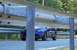 Highway railings fenced asphalt road and blue sedan on the road photo