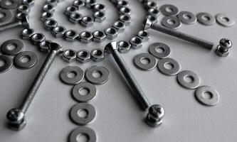 Part Of Design Pattern Of Steel Fasteners And Bolts In Star Shape On White Surface photo