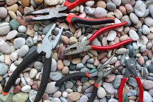 Concept Photo With Set Of Different Types Of Mechanics Pliers On Smooth Rocks Top View