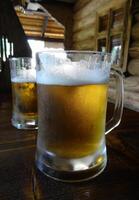 Two full glasses of light beer on the table at pub in country style photo