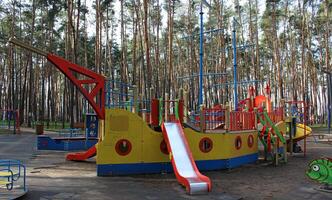 Outdoor game complex with children's slides in the form of a ship with masts in the recreational area photo