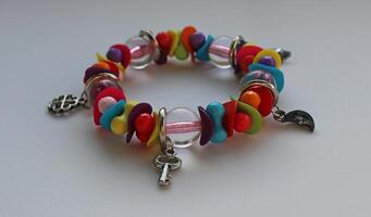 Multi colored beads and silver charms in one wrist bracelet isolated on white angle view photo