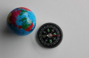 Route Navigation Concept. Top View Of Globe Model And Compass On White Backdrop photo