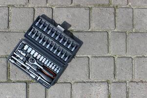 A set of repairing tools in a plastic case on a concrete paving slabs photo