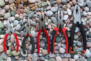 Slip Joint Pliers, Groove Pliers, Needle Nose Pliers And Linesman Pliers Laid Out Arranged On Size On A Stones Background photo