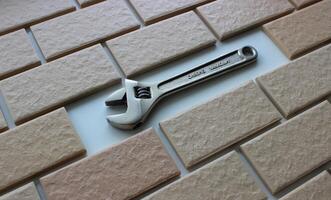 An adjustable spanner in place of a missing tile on a fully tiled surface photo