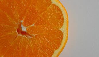 Juicy orange slice on a white surface at the side of the image. Stock photo for citrus fruits backgrounds