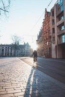 Man rushing to work on his bicycle during sunrise in the city centre of Ghent, Belgium. Bicycle as the main means of transport. Ecological engineering photo