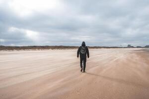 Man walks on a sandy beach in the face of high winds near Blankenberge, west coast of Belgium. Exploring and discovering Belgium photo