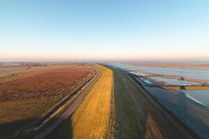 Embankment protecting residents in the southern Netherlands from ocean water under a brilliant orange-yellow sunrise. Breathtaking morning photo