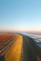 Embankment protecting residents in the southern Netherlands from ocean water under a brilliant orange-yellow sunrise. Breathtaking morning photo